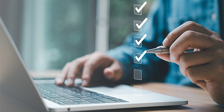 Business owner conducting due diligence when selling a business with a computer and checklist.